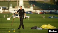 Seorang polisi membawa ikat pinggang sebagai bukti di lokasi seorang laki-laki membakar dirinya di Monumen Nasional, Washington DC (4/10). (Reuters/Gary Cameron)