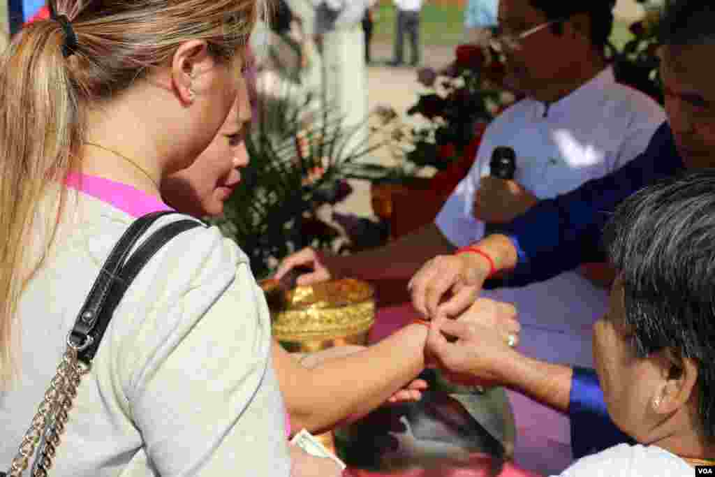 អ្នកកាន់ពុទ្ធសាសនាចងខ្សែអំបោះដើម្បីទទួលសិរីសួស្ដី។ (ចាប ចិត្រា/VOA)