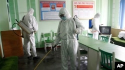 Petugas tengak menyemprotkan disinfektan di kantor RS Phyongchon District People di Pyongyang, Korea Utara, 1 April 2020.