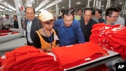 Prime Minister Hun Sen, center, leans over a garment worker during a visit to a factory outside of Phnom Penh, Cambodia, Aug. 30, 2017.