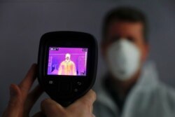FILE - An infrared camera is shown scanning a person for elevated body temperature at a General Motors plant in Warren, Michigan, April 23, 2020.