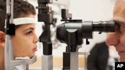 FILE - Dr. Albert Maguire checks the eyes of Misa Kaabali, 8, at the Children’s Hospital of Philadelphia, Oct. 4, 2017. Misa was 4 years old when he received his gene therapy treatment.