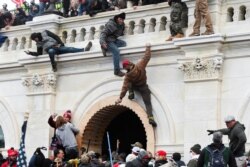 Algunos manifestantes se encaraman a las paredes del Capitolio durante los disturbios.