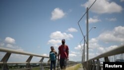 Dos inmigrantes venezolanos cruzan el Puente de Unidad Nacional en Guayaquil, Ecuador, en abril de 2020, tras ser declarada la pandemia mundial de COVID-19.