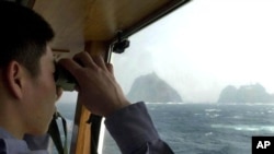 In this April 28, 2005, file photo, a South Korean coast guard looks at Dokdo islets, known as "Takeshima" in Japanese, through a telescope on the patrol ship Sambong-ho on the East Sea, South Korea. 