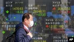 A man walks by an electronic stock board of a securities firm in Tokyo, Jan. 20, 2021.