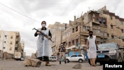 FILE PHOTO: Security men wearing protective masks stand on a street during a 24-hour curfew amid concerns about the spread of the coronavirus disease (COVID-19), in Sanaa, Yemen May 6, 2020.
