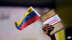 Una mujer sostiene una bandera venezolana y un libro sobre la disputa del territorio del Esequibo en Caracas, el 29 de noviembre de 2023. 