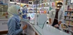 FILE - People wearing protective masks shop at a pharmacy in the Iranian capital Tehran, Feb. 24, 2020.