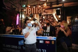 FILE - A medical worker prepares to administer a vaccination against COVID-19 as part of a Tel Aviv municipality initiative offering a free drink at a bar to residents getting the shot, in Tel Aviv, Israel, Feb. 18, 2021.