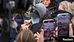 Um homem que esconde o rosto é rodeado pela polícia francesa, jornalistas e manifestantes quando sai após o veredito no julgamento de Dominique Pelicot, no tribunal em Avignon, França, 19 de dezembro de 2024