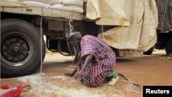 A man gathers rice spilled from a humanitarian food convoy that arrived from the Malian capital Bamako in the northeastern city of Gao, June 12, 2012. 