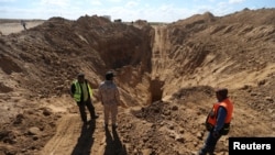 FILE - Rescue workers and a member of Palestinian security forces loyal to Hamas, stand while searching for missing or dead militants after Israel blew up a cross-border tunnel, in Khan Younis in the southern Gaza Strip, Nov. 3, 2017.
