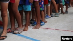 ARCHIVO - Niños migrantes venezolanos hacen fila dentro de un coliseo donde se ha instalado un campamento temporal, luego de huir de su país, según la agencia colombiana de migración, en Arauquita, Colombia, 26 de marzo de 2021.