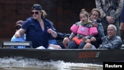 People ride a boat though flood water after being evacuated from the rising water following Hurricane Harvey in a neighborhood west of Houston, Texas, U.S., August 30, 2017.