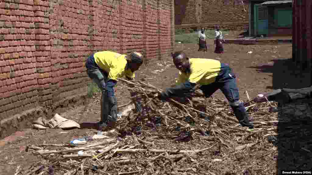 Deux jeunes employés de Briquettes du Kivu étalent au soleil les déchets organiques qu'ils ont tiré d'un champs après récolte, à Bukavu, en RDC, le 30 mai 2018. (VOA/Ernest Muhero)