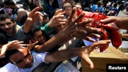 Syrian refugees and other migrants struggle to get dry food during aid distribution by municipality workers on the Greek island of Kos, Aug. 14, 2015. 
