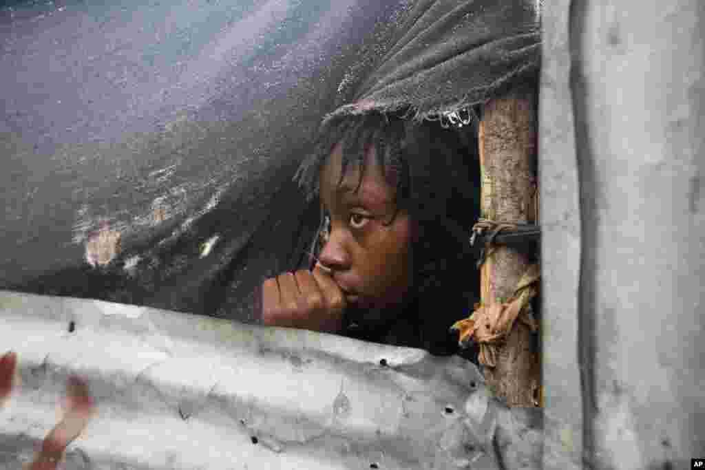 Seorang anak perempuan mengintip dari jendela rumahnya di Tabarre, Haiti, saat pihak berwenang tiba untuk mengevakuasi warga (3/10). (AP/Dieu Nalio Chery)