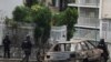 Miembros de la Unidad de Operaciones Tácticas Especiales, pasan frente un vehículo carbonizado en el barrio Cota 905, en Caracas, el 9 de julio de 2021.