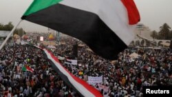 Thousands of protesters wave Sudanese flags, hold banners and chant slogans during a demonstration in front of the Defense Ministry in Khartoum, Sudan, April 18, 2019. 