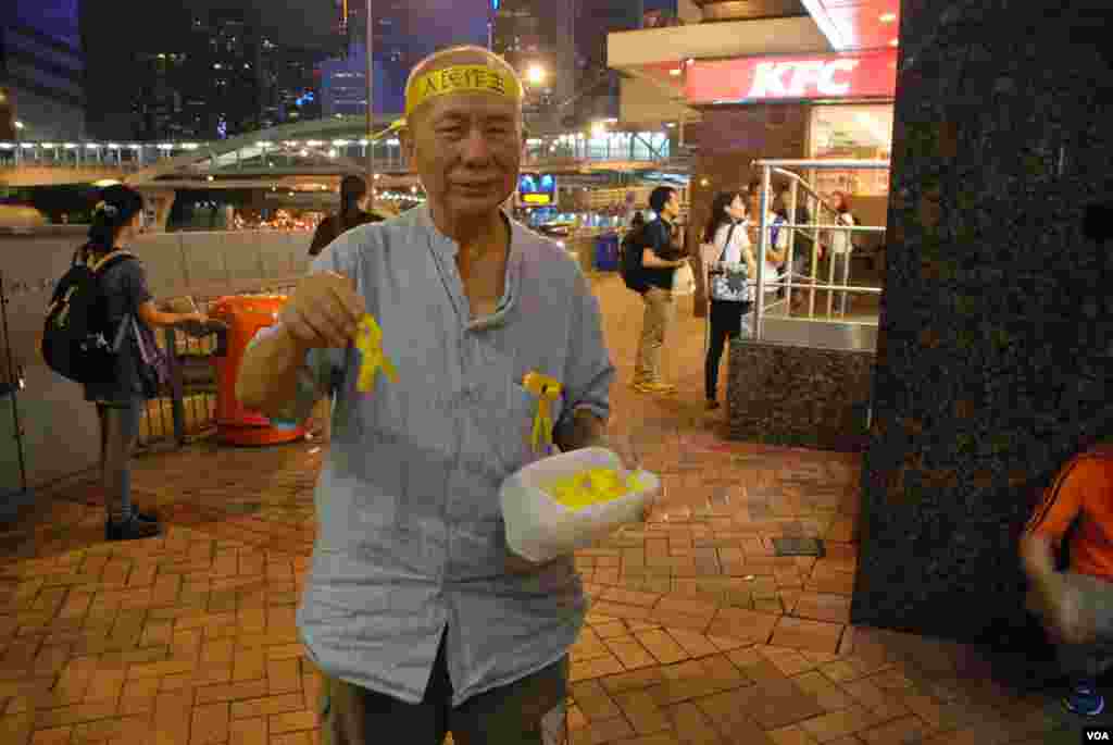 年約70歲的香港市民黃伯伯在前往罷課集會場地添馬公園的主要通路,向途人派發代表真普選的黃絲帶