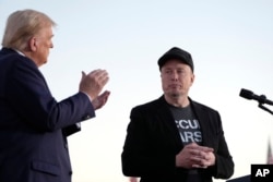 FILE - U.S. President Donald Trump, left, claps as Tesla and SpaceX CEO Elon Musk prepares to depart after speaking at a campaign event at the Butler Farm Show, on Oct. 5, 2024, in Butler, Pennsylvania.