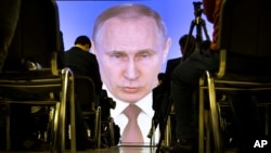 Journalists watch as Russian President Vladimir Putin gives his annual state of the nation address in Manezh in Moscow, Russia, Thursday, March 1, 2018. (AP Photo/Alexander Zemlianichenko)