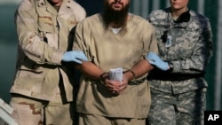 FILE - A shackled detainee is being escorted away from an Administrative Review Board hearing, at Camp Delta detention center at the Guantanamo Bay U.S. Naval Base in Cuba, Dec. 6, 2006.