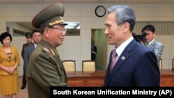 South Korean presidential security adviser Kim Kwan-jin, right, shakes hands with Hwang Pyong So, North Korea's top political officer for the Korean People's Army, after meeting at the border village of Panmunjom in Paju, South Korea, Aug. 25, 2015. 