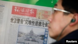 Seorang pria berdiri di depan salinan koran Global Times yang menampilkan foto pelantikan Presiden AS Joe Biden di Beijing, China, 21 Januari 2021.