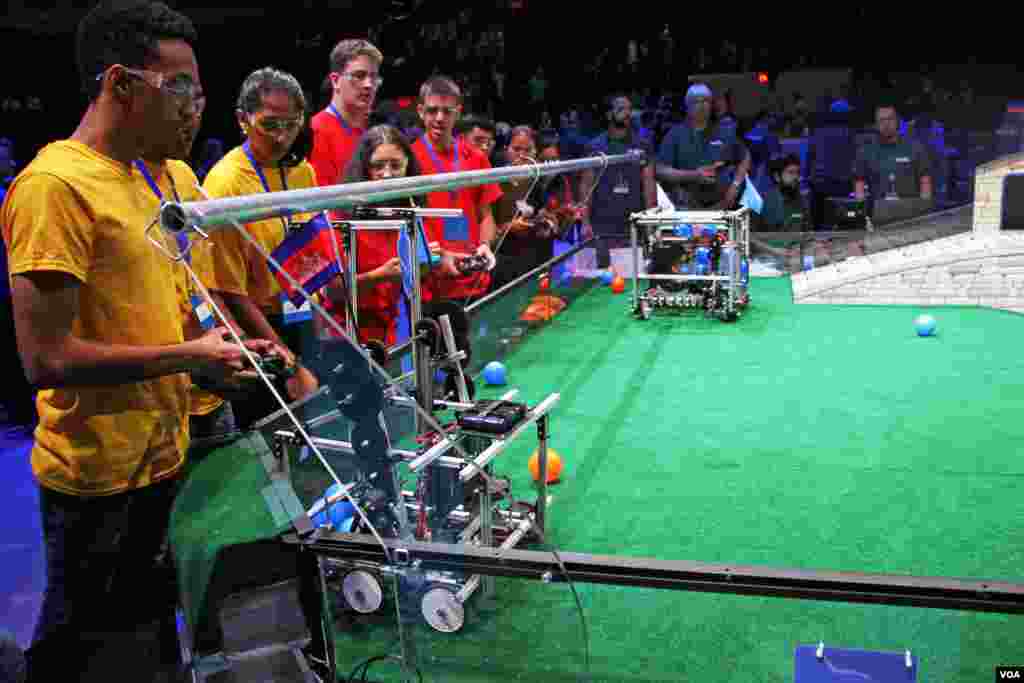 The robot of the Cambodian team tries to catch a ball the in front of the Guyana team (left, yellow), during First Global Challenge robotics competition in Washington, DC, Monday, July 17, 2017. (Nem Sopheakpanha/VOA Khmer)