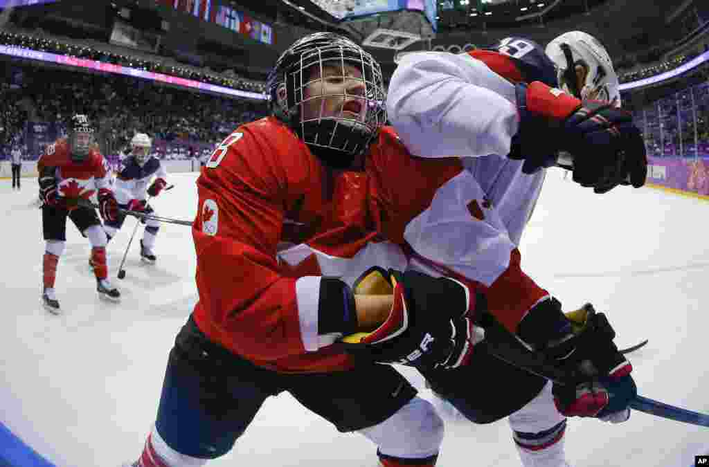 Laura Fortino of Canada (8) gets an elbow in her mask from Jocelyne Lamoureux of the United States (17) during the third period of the women's gold medal ice hockey game at the 2014 Winter Olympics, Feb. 20, 2014.