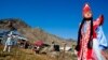 At the Chui Oozi cultural center, a young woman shows off traditional native dress . In the background, Bolot Byiryshev, one of Altai’s most accomplished throat singers, rests after singing an epic ballad. VOA Photo: Vera Undritz 
