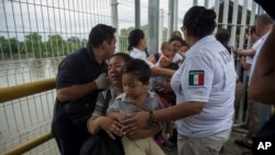 Une mère migrante du Honduras et son fils traversent le pont après avoir franchi la frontière entre le Guatemala et le Mexique, à Ciudad Hidalgo, au Mexique, le samedi 20 octobre 2018. 