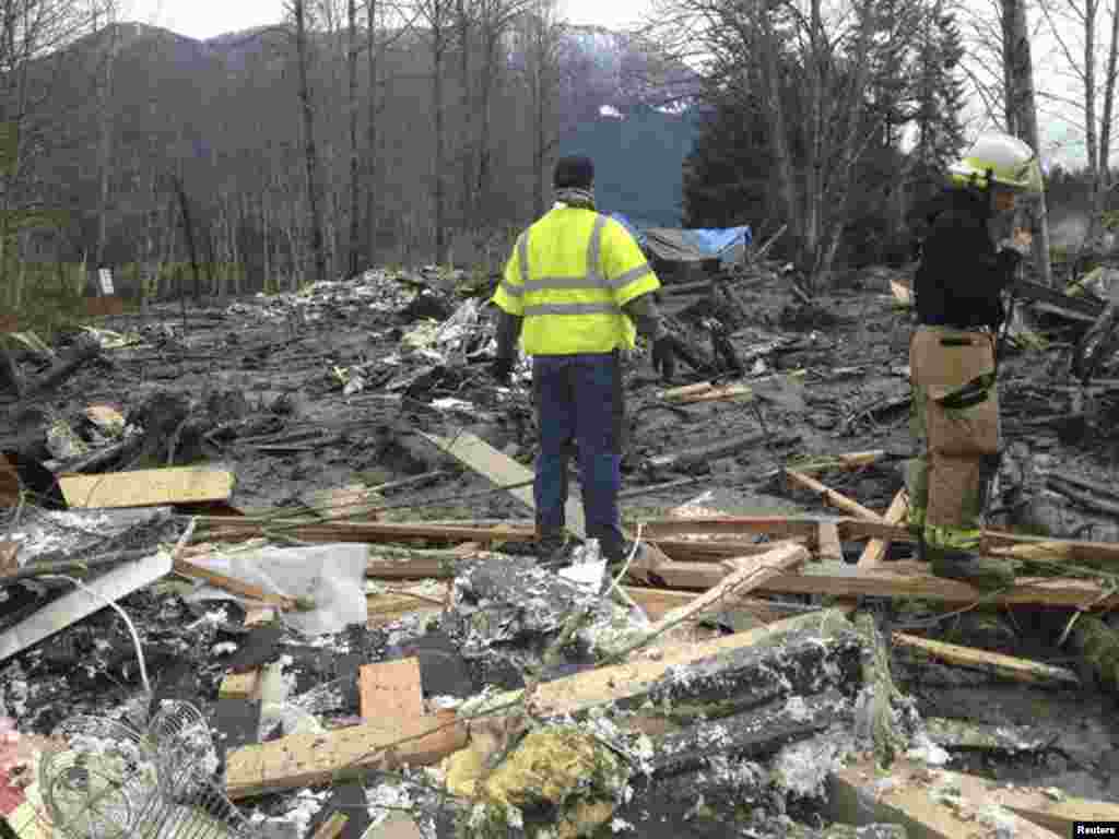 Officials survey a large mudslide that pushed debris and at least one house onto Highway 530 near Oso, Washington, March 22, 2014.