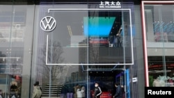 FILE - People walk past an ID. Store X showroom of SAIC Volkswagen in Chengdu, Sichuan province, China, Jan. 10, 2021.