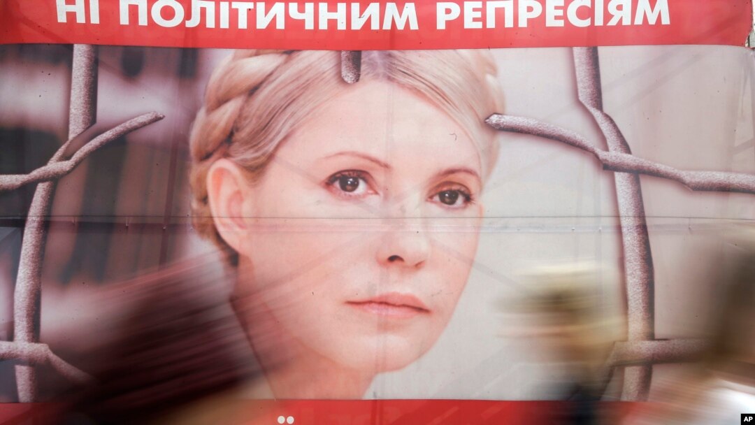 FILE - People pass by a poster of Ukraine's imprisoned former Prime Minister Yulia Tymoshenko at a tent camp of her supporters in central Kiev, Ukraine. 