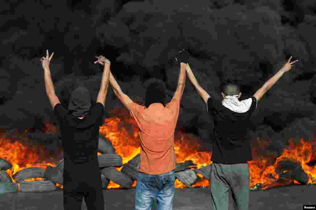 Manifestantes palestinos miran neumáticos en llamas durante una protesta por la tensión en Jerusalén y la escalada entre Israel y Gaza, en la Cisjordania ocupada por Israel.