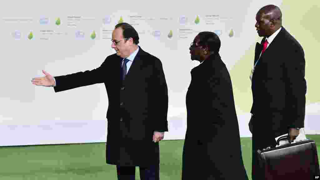Zimbabwe's President Robert Mugabe is greeted by French President Francois Hollande, left, as he arrives for the COP21, United Nations Climate Change Conference, in Le Bourget, outside Paris, Monday, Nov. 30, 2015.