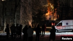 Local residents gather near a residential building as a critical power infrastructure object burns after a Russian drone attack, amid Russia's attack on Ukraine, in Kyiv, Ukraine Dec. 19, 2022. 