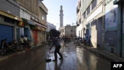 Des personnes en train de nettoyer les débris de la rue suite à une crue mortelle dans la ville de Dar Chaabane, en Tunisie, le 23 septembre 2018.