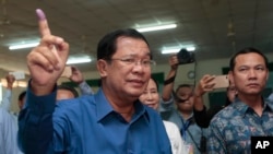 Cambodian Prime Minister Hun Sen of the Cambodian People's Party shows off his inked finger after voting in local elections at Takhmau polling station in Kandal province, southeast of Phnom Penh, Cambodia, Sunday, June 4, 2017. (AP Photo/Heng Sinith)