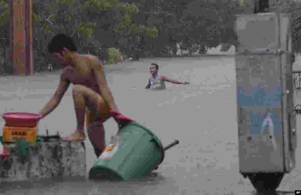 A man wades in chest-deep floods as another retrieves his belongings in Quezon City, north of Manila, Philippines, August 7, 2012.