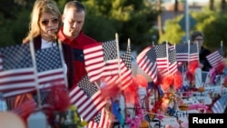 FILE - A couple looks over 58 wooden crosses, with the names and photos of the October 1 mass shooting victims, in the median of Las Vegas Boulevard South near the "Welcome to Las Vegas" sign in Las Vegas, Nevada, Oct. 9, 2017.