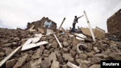 A youth throws a plank of wood away from a pile of rubble of a house destroyed during an air strike carried out by the Saudi-led coalition in Faj Attan village, Sanaa, Yemen, May 7, 2015.