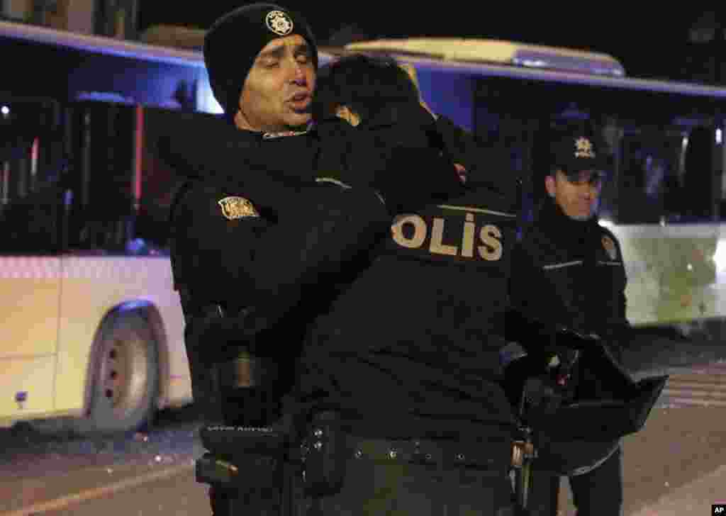 Police officers comfort each other after explosions near the Besiktas football club stadium Vodafone Arena in Istanbul, Dec. 10, 2016.