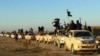FILE - This undated file image posted on an extremist website on Jan. 14, 2014, shows fighters from the Islamic State group marching in Raqqa, Syria.