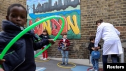 Children use hoops for social distancing at L'Ecole des Petits, an independent French bilingual school, as the coronavirus disease (COVID-19) lockdown eases in Fulham, London, June 9, 2020.