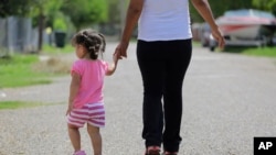 In this 2015 photo, in Sullivan City, Texas, a woman who is in the country illegally walks with her two-year-old daughter who was born in the in the United State but was denied a birth certificate.(AP Photo/Eric Gay)