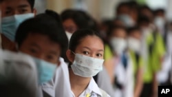 FILE - Students line up to sanitize their hands to avoid contact with the coronavirus before their morning class at a high school in Phnom Penh, Cambodia, Jan. 28, 2020. 